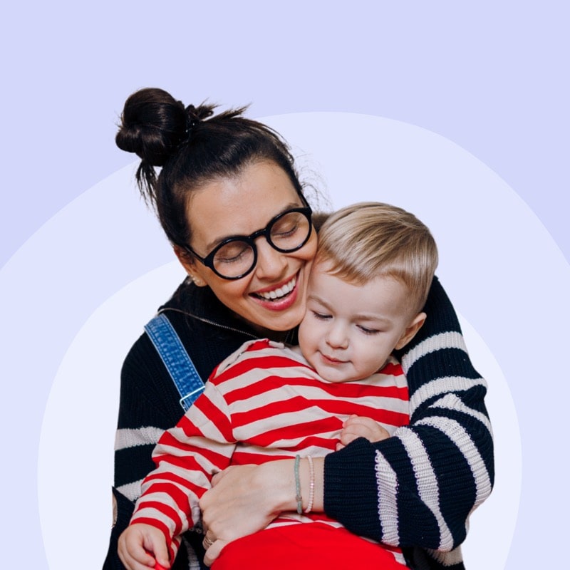 A childminder cuddling a young child