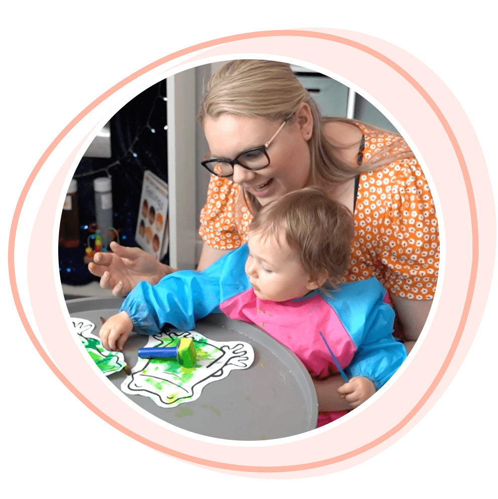 Smiling childminder doing sponde paints with a child